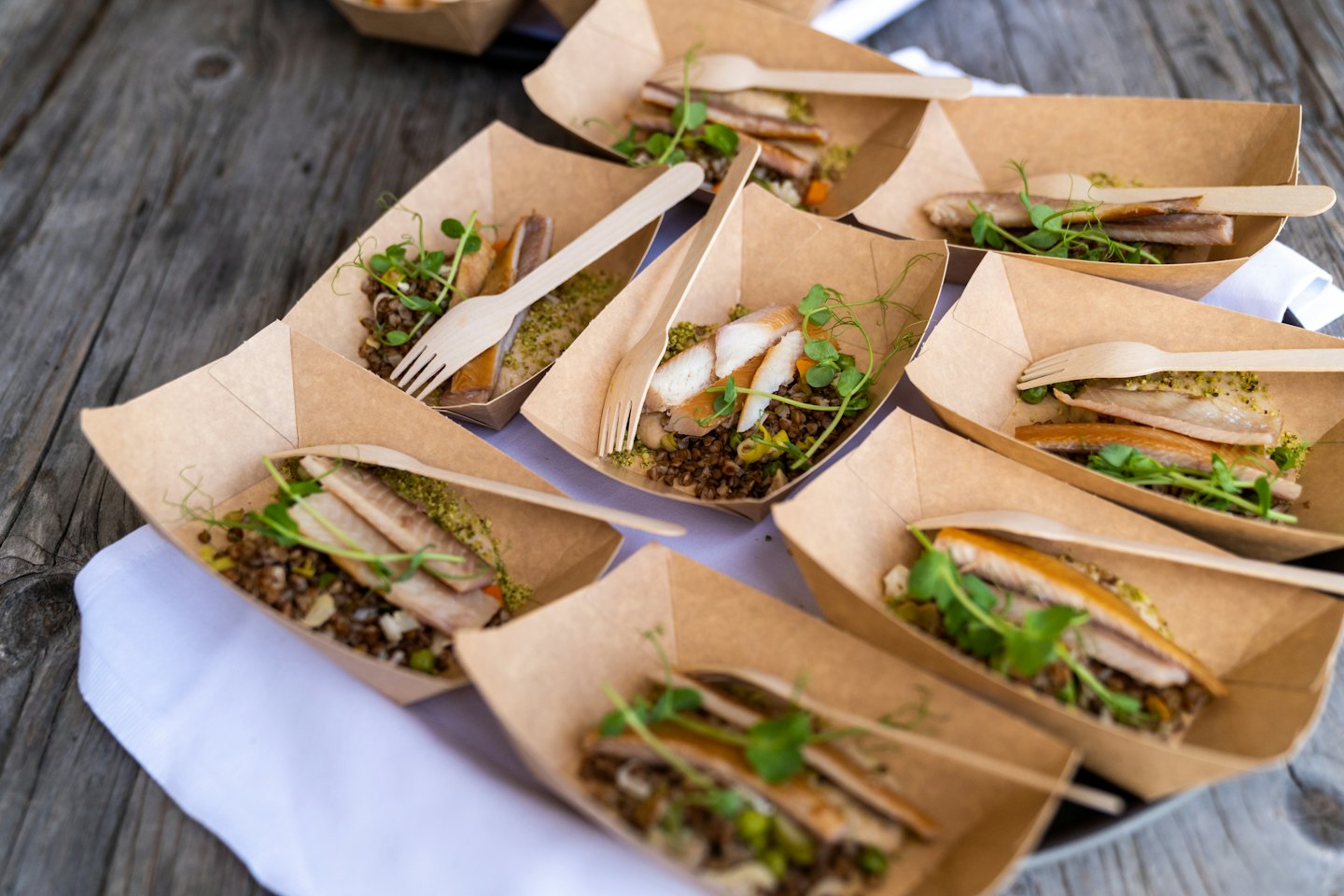 Healthy meals in brown trays with wooden forks on a table.