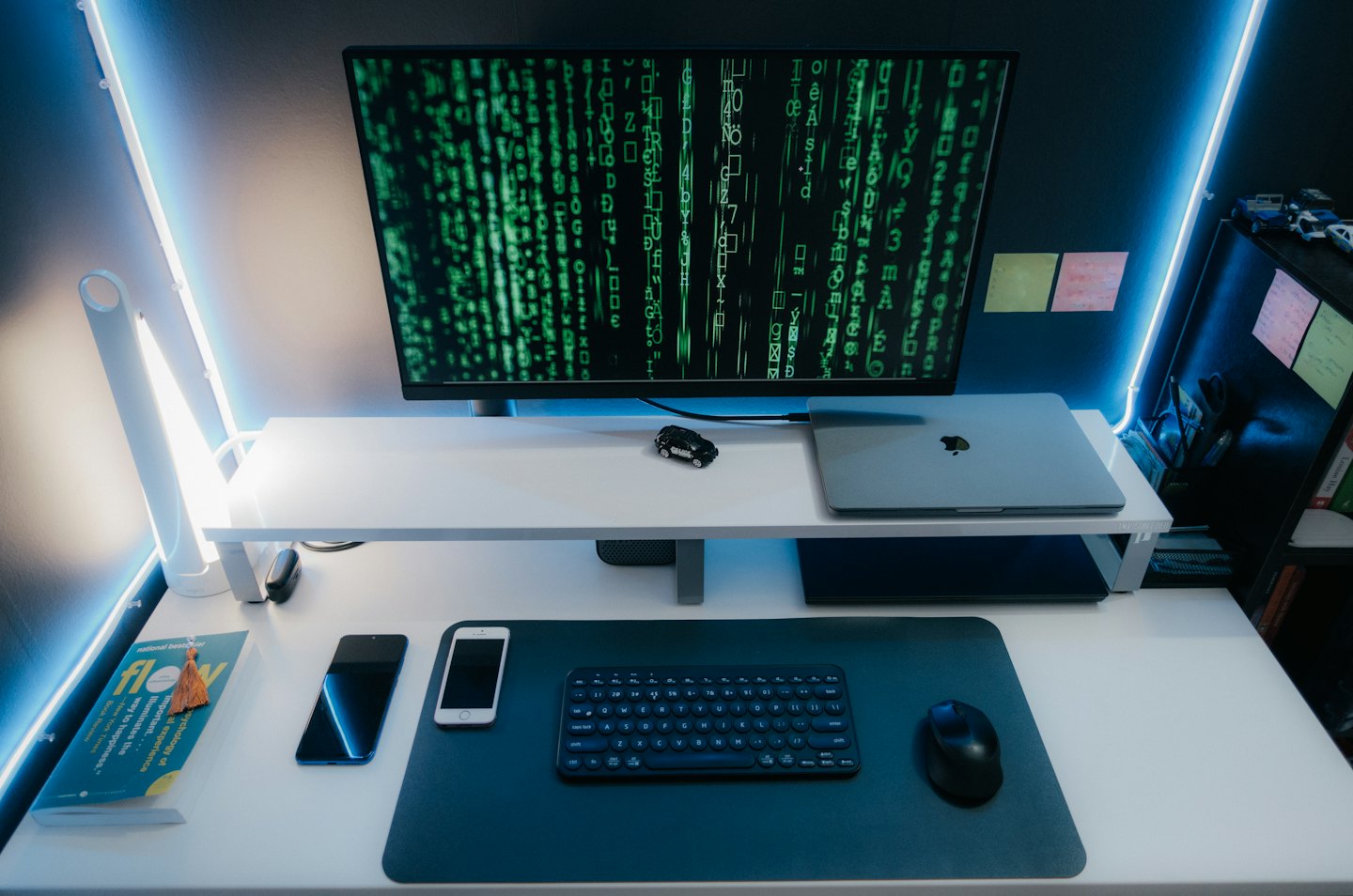 Computer monitor with green code and modern desk accessories.