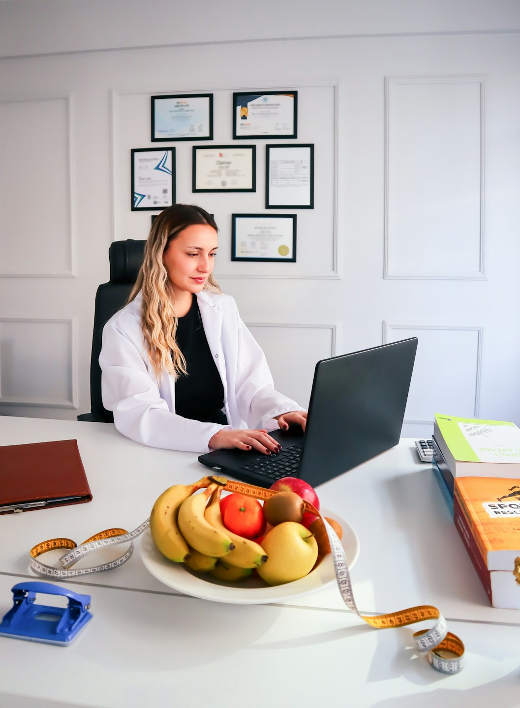 Nutritionist working on a laptop at a desk with fruit.