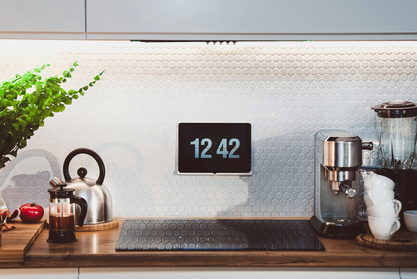 Modern kitchen counter with tablet, kettle, and espresso machine.