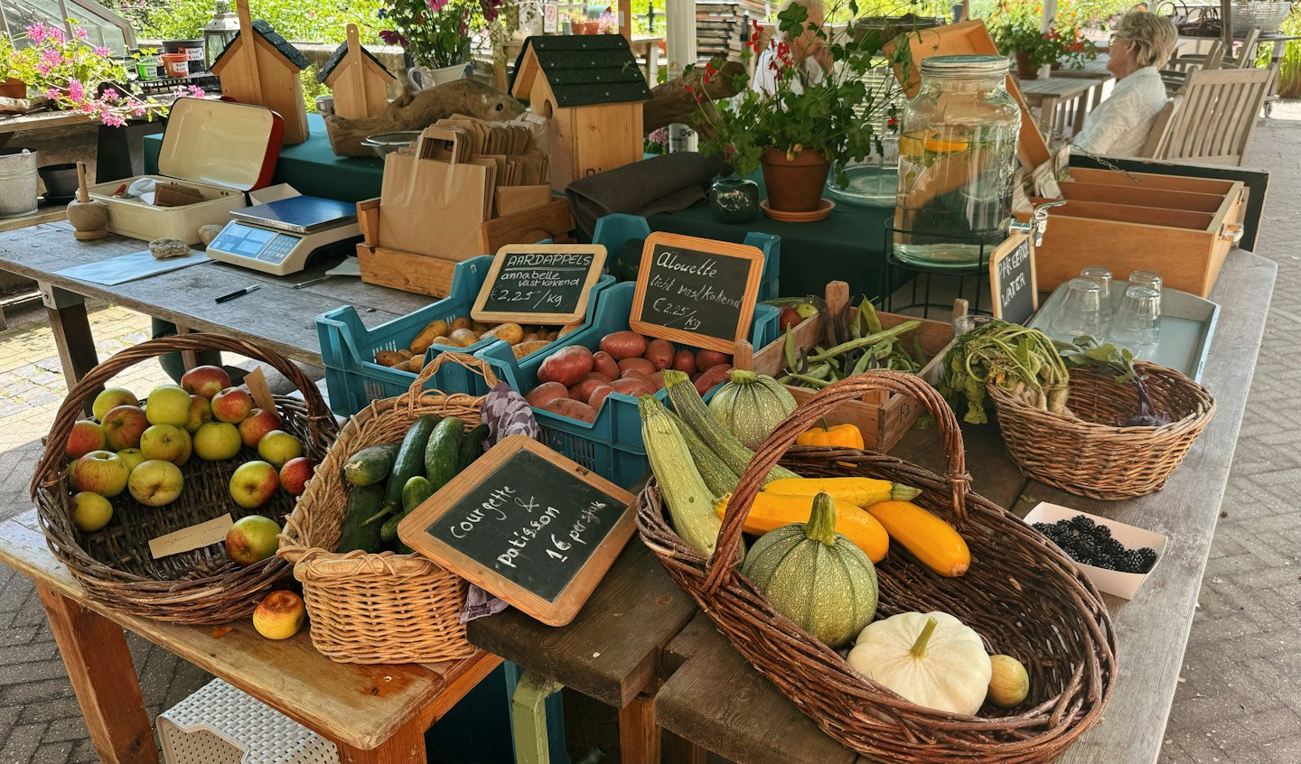 Fresh produce at an outdoor market stall with shoppers in the background.